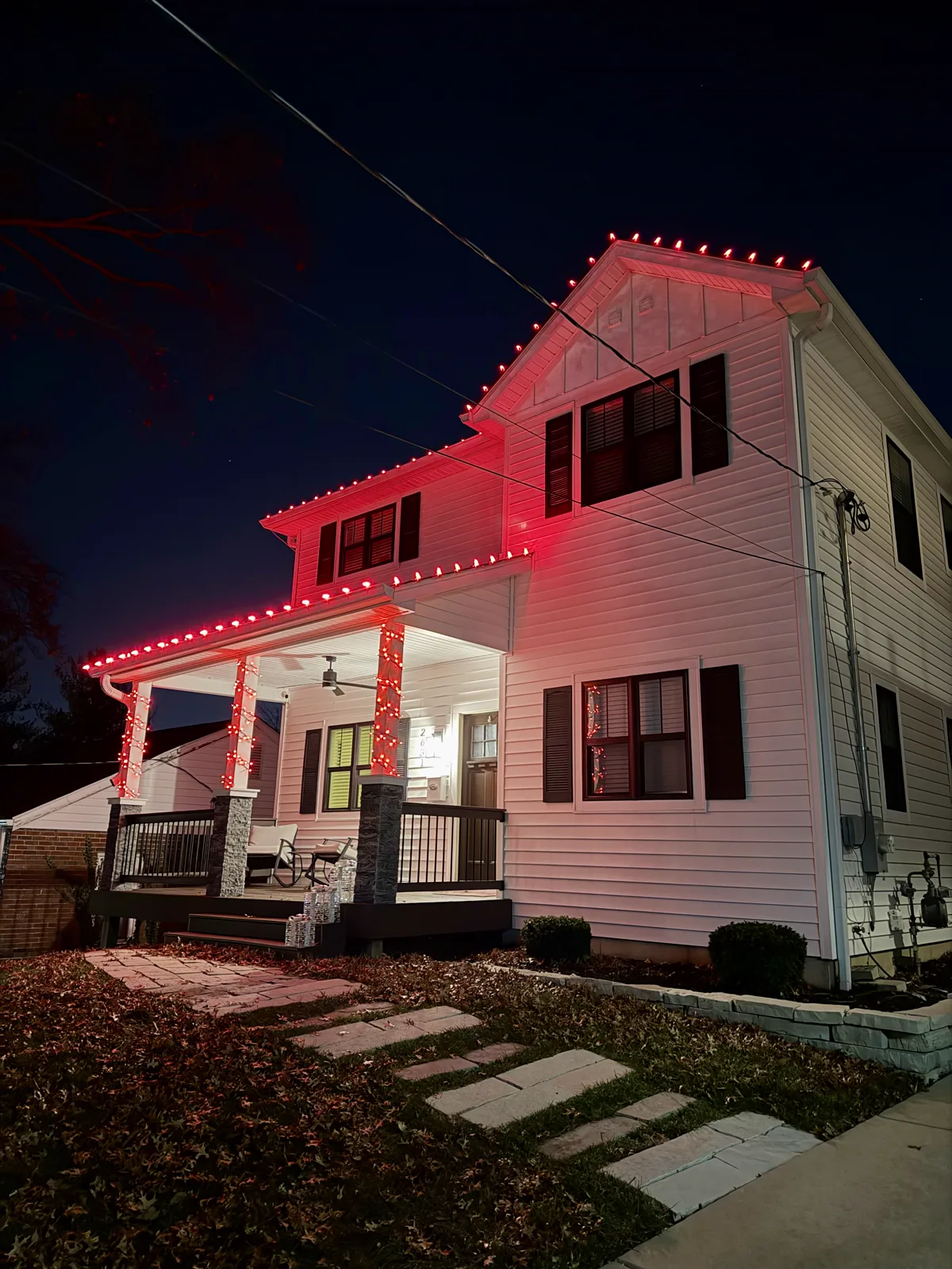 All-red C9 roofline and porch lighting on a white two-story home