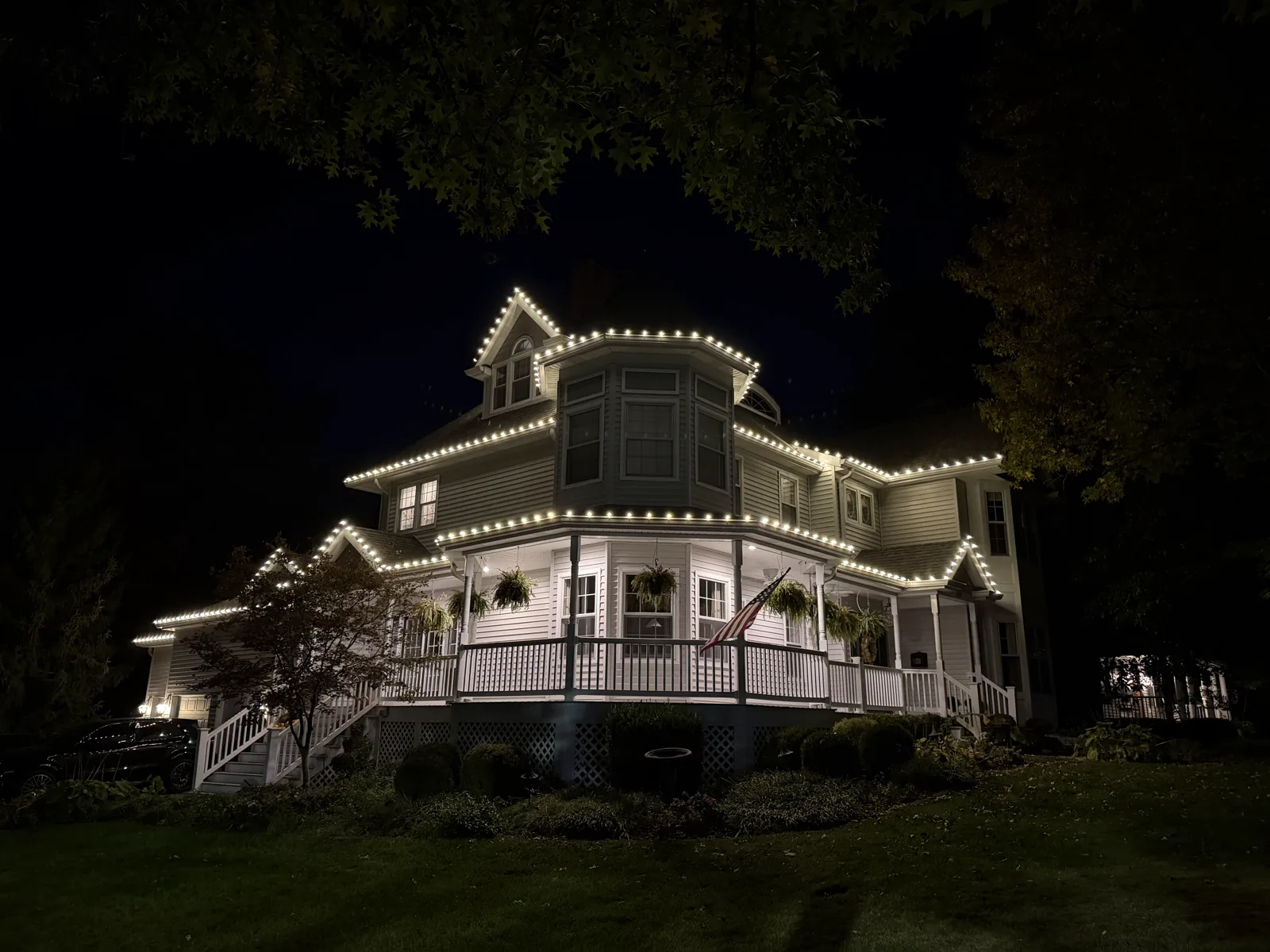 Warm-white C9 roofline lights on a white Victorian home with a wraparound porch