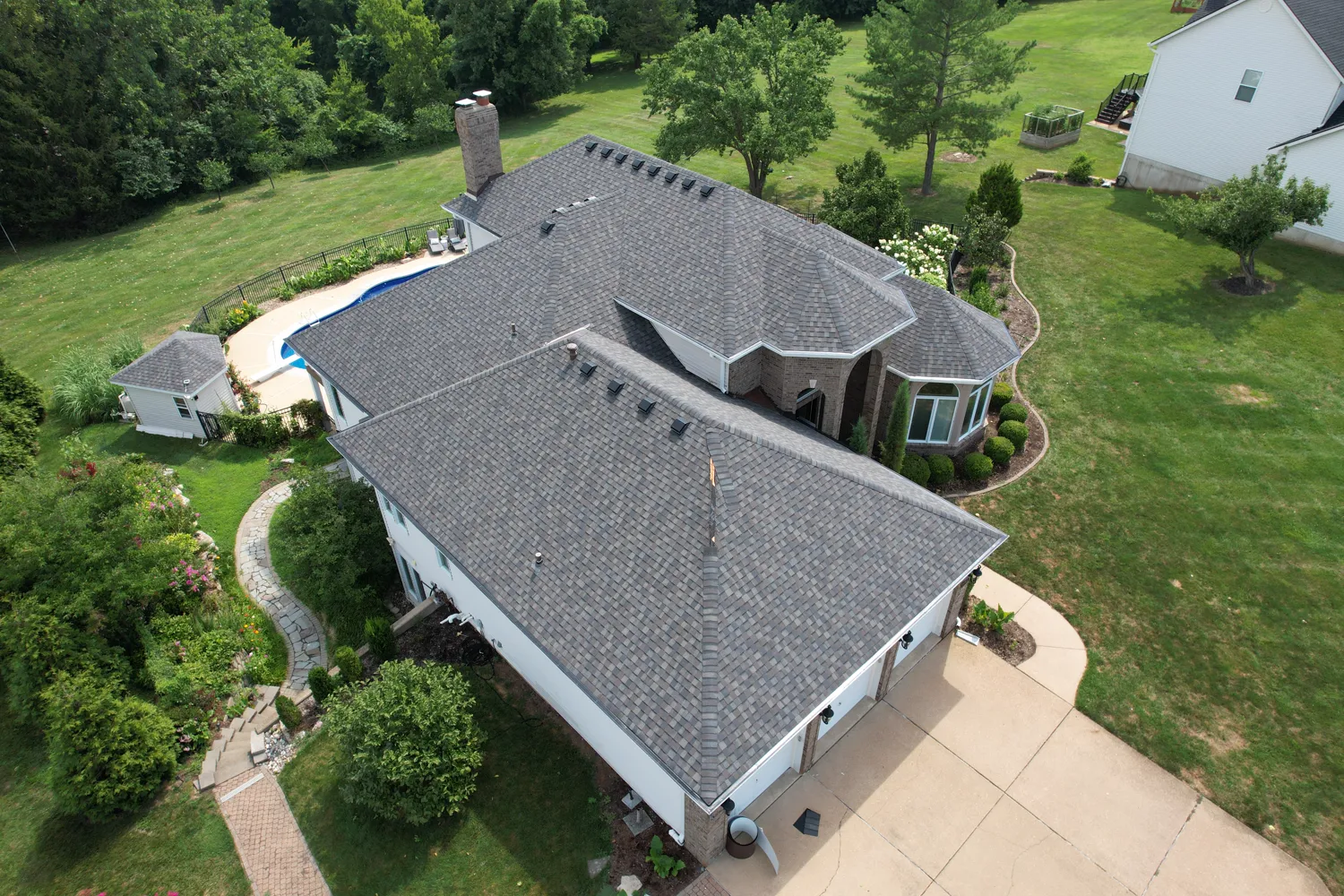 Completed architectural-shingle roof on a large brick estate with an in-ground pool near St. Louis
