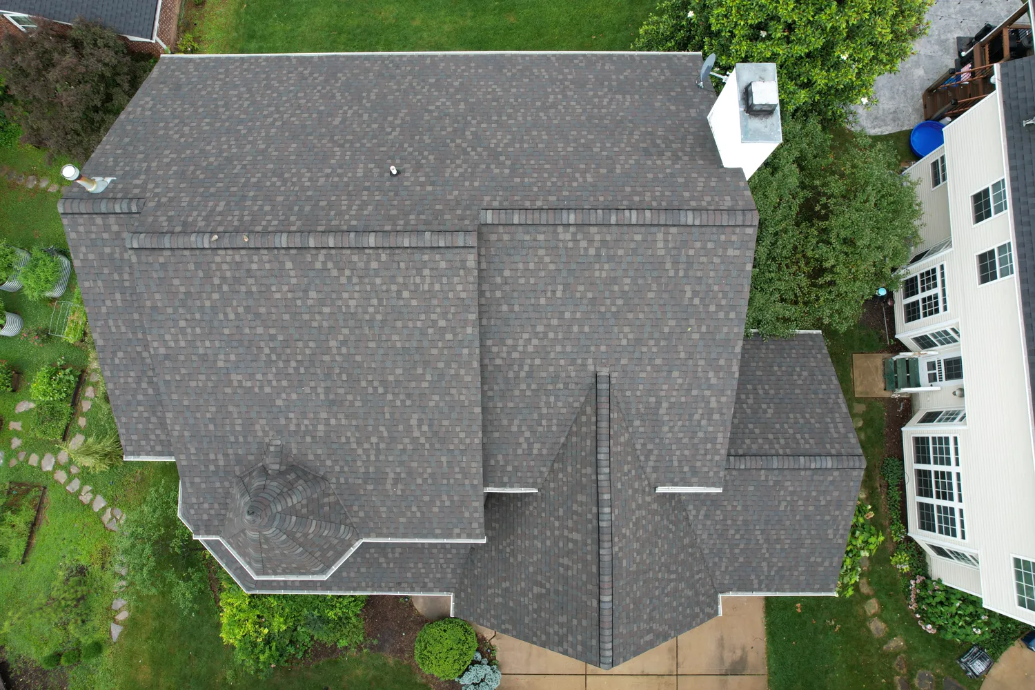 Aerial view of a completed architectural-shingle roof on a home with a turret
