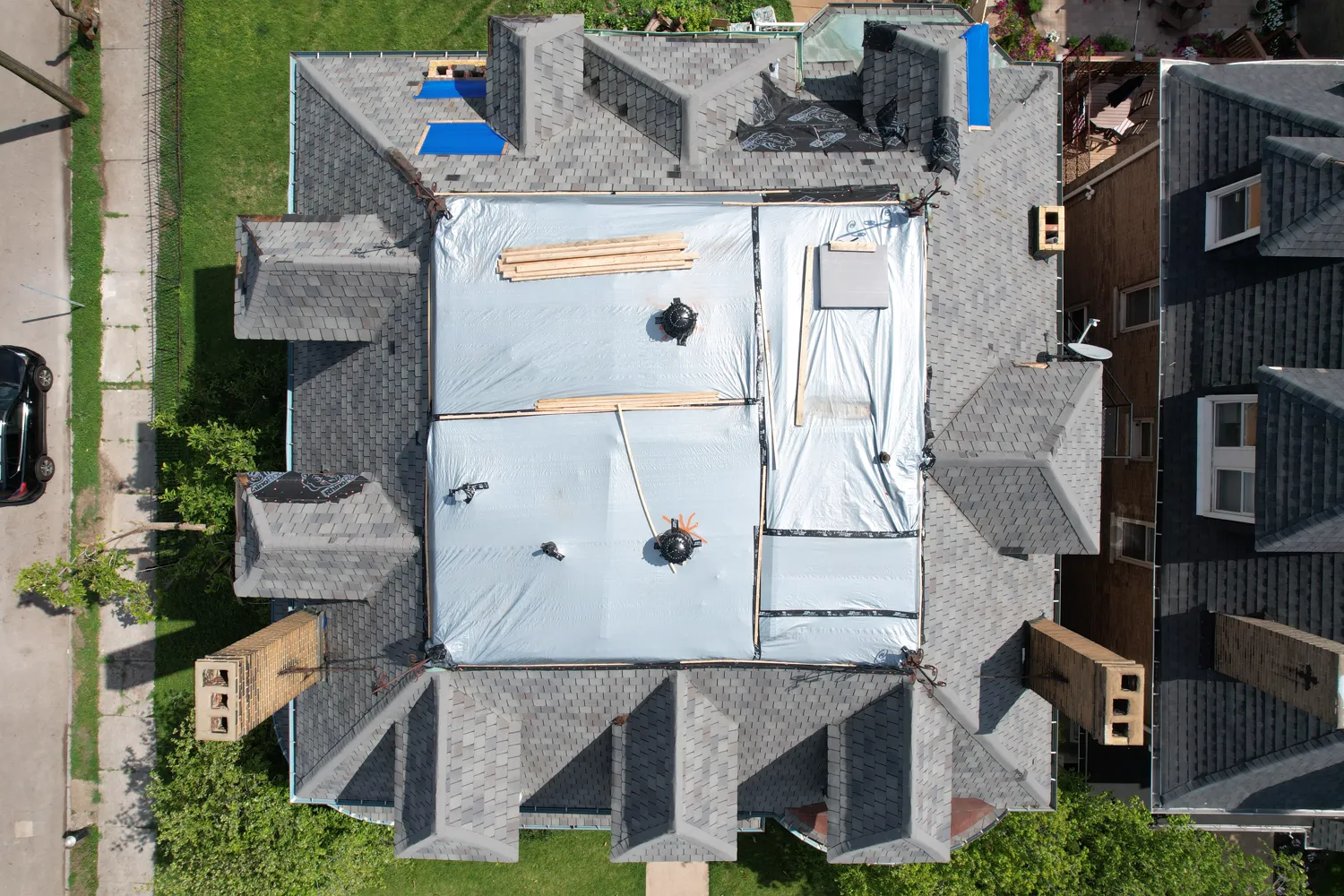 New shingles going on the steep, ornate hip roof of a historic St. Louis home