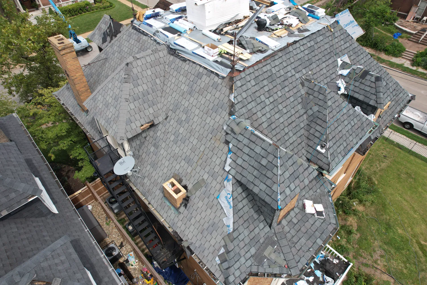 Roof replacement in progress with materials staged across a complex St. Louis roofline