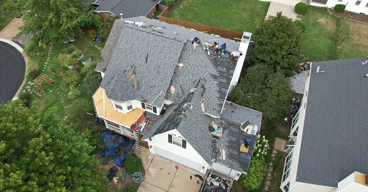 Roofers installing shingles on a complex roof with a turret and multiple valleys